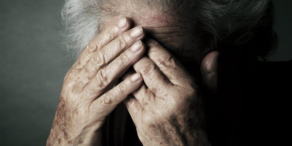 MODEL RELEASED. Depressed elderly woman, covering her face with her hands.